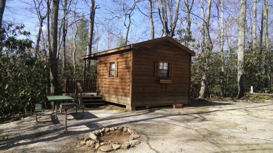 Rustic cabin nestled in the woods at Linville Falls Campground, with a fire pit for outdoor gatherings