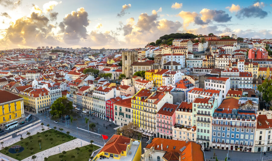 Aerial view of Lisbon cityscape, featuring historic architecture, terracotta roofs, and a vibrant plaza.