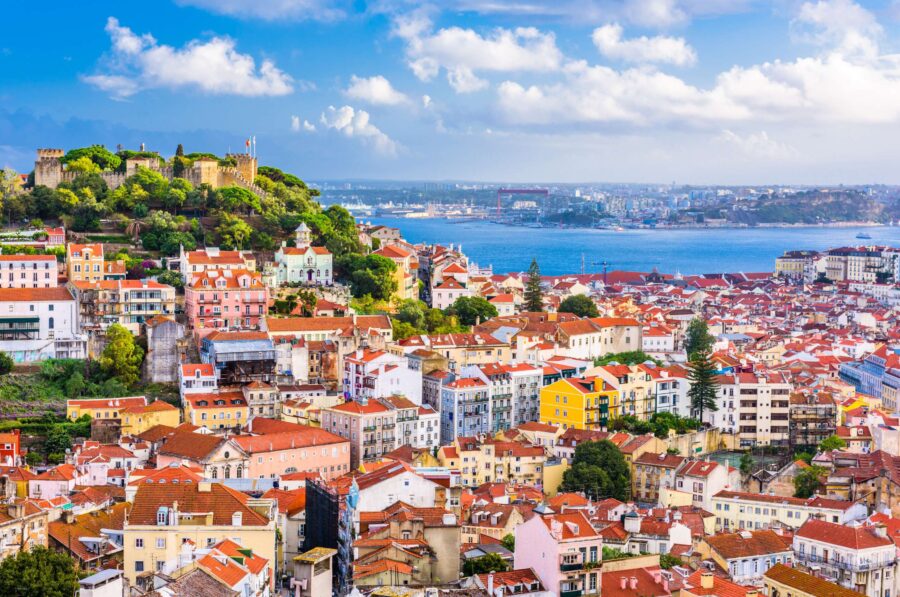 Panoramic view of Lisbons historic castle, terracotta rooftops, and vibrant coastal cityscape.