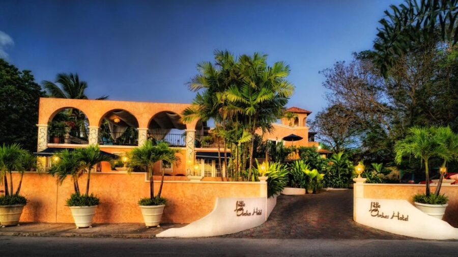 Entrance to Little Arches Boutique Hotel in Barbados, featuring palm trees and an elegant gate.