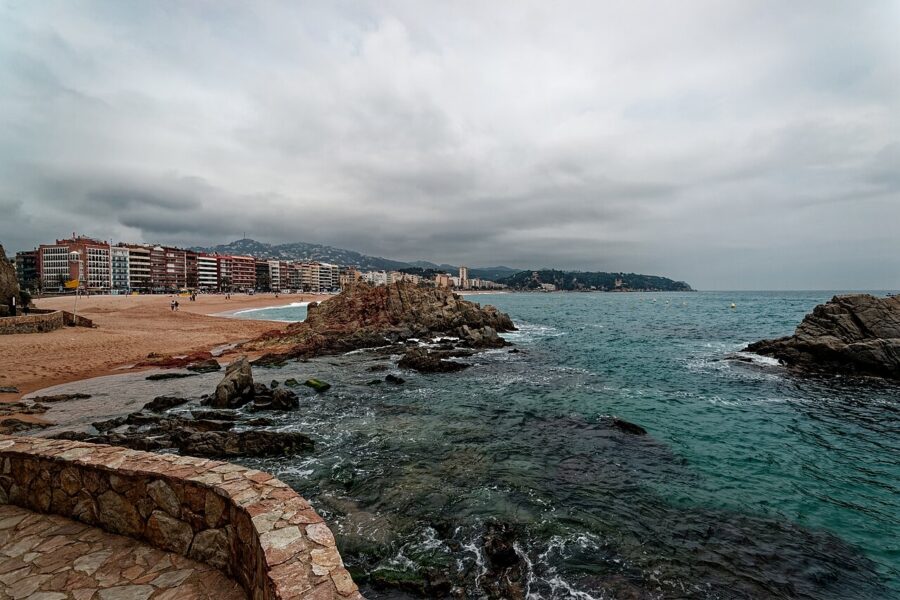 Panoramic view of Lloret de Mar beach and buildings under a cloudy sky.