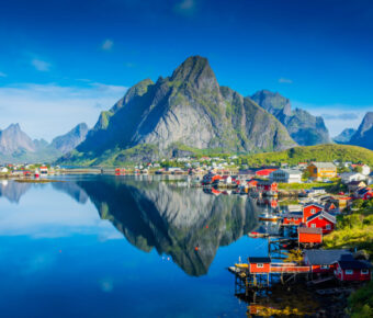 Stunning reflection of Reine village mirrored in the tranquil fjord waters of Norway's Lofoten Islands.