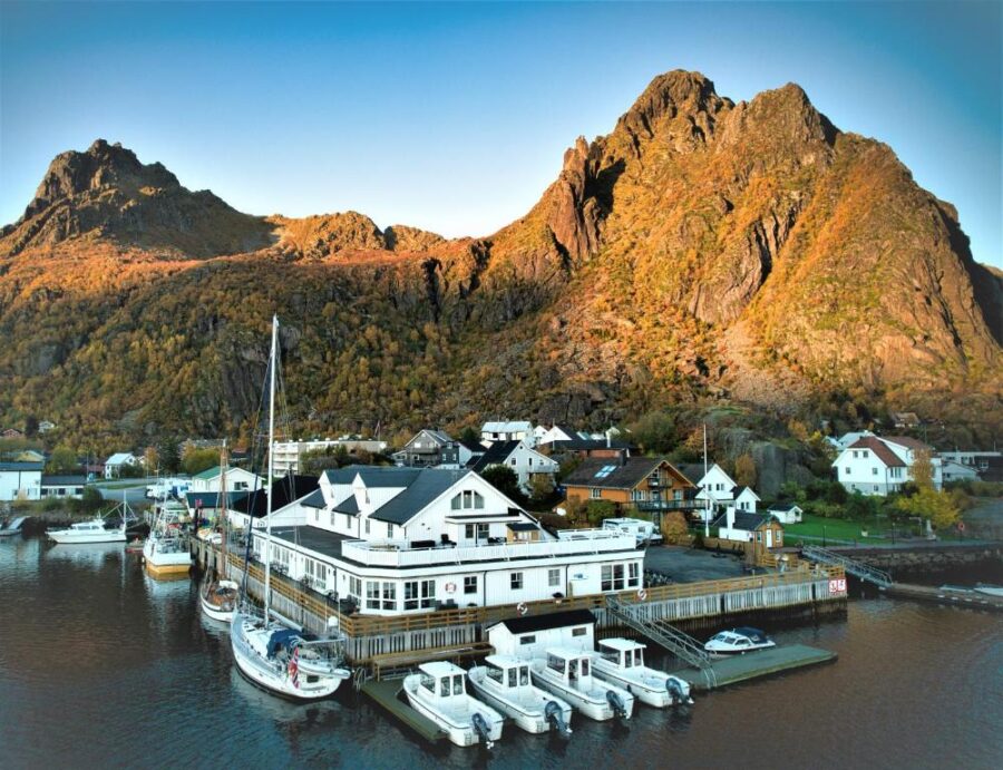 Scenic view of a boat dock at Lofoten Rorbuer, framed by a towering mountain in the background.
