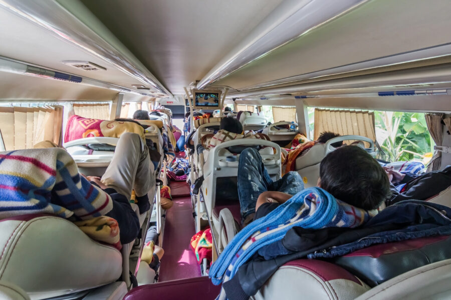 Cozy interior of a sleeper bus featuring passengers resting on reclining seats during a long journey