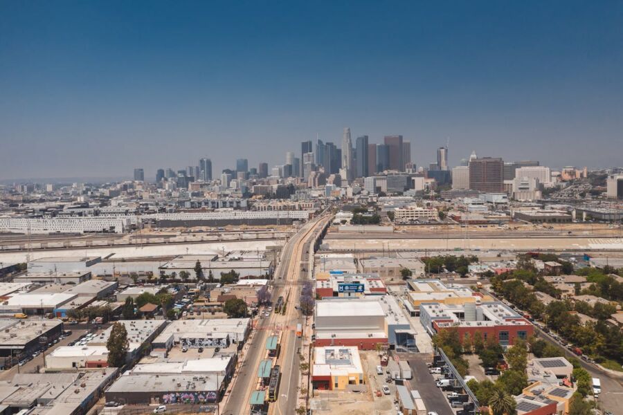 Downtown L.A skyline: modern skyscrapers, urban landscape with railways, greenery, and industrial structures.