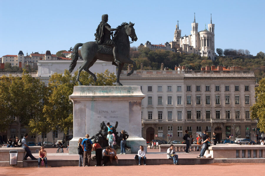 Equestrian statue of Louis XIV, vibrant urban square with people, basilica in background.