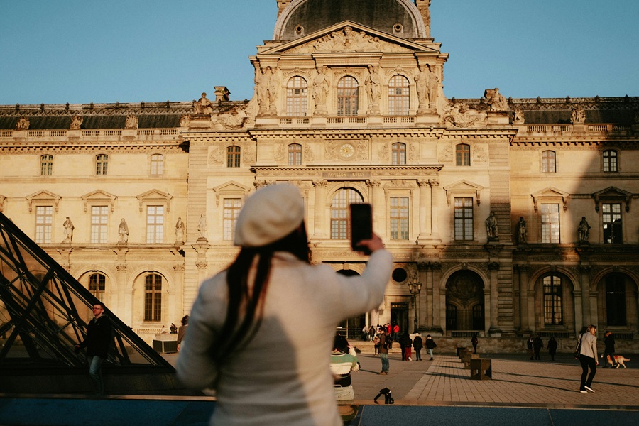 Visitors enjoying the Louvre Museums architecture and the iconic glass pyramid in Paris.