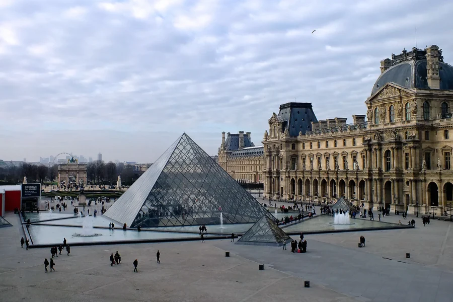 The Louvre Museum, Paris, with iconic glass pyramid entrance and historic architecture.