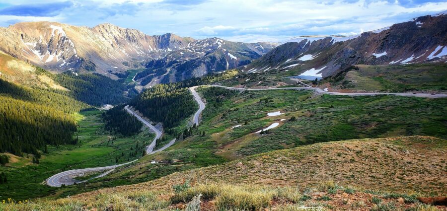 Scenic panorama of Loveland Pass, showcasing a winding road amidst vibrant green foliage in the Colorado mountains.
