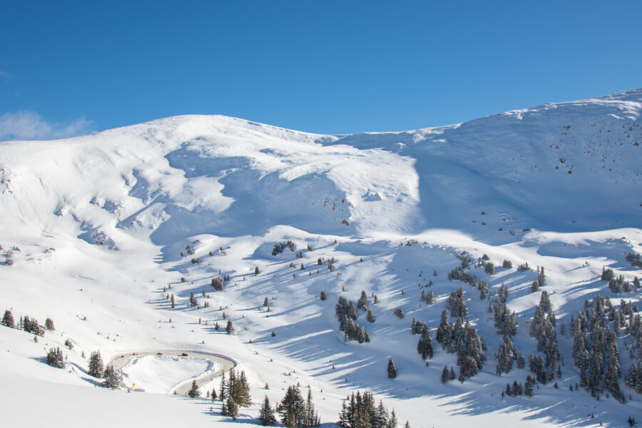 Aerial view of Loveland Pass showcasing snow-covered mountains and winding roads under a clear blue sky