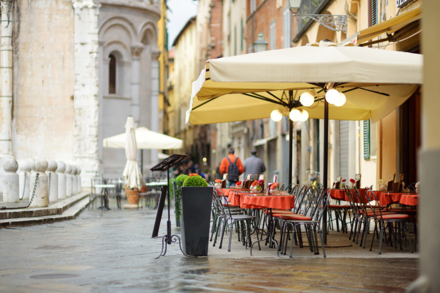 Outdoor cafe in Lucca, Italy, featuring beautifully decorated tables and chairs set against a charming city backdrop.