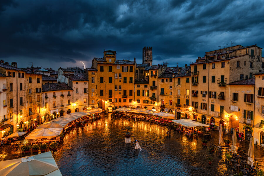 Night view of a plaza in Lucca, Italy, illuminated by soft lights, showcasing historic architecture and a serene atmosphere