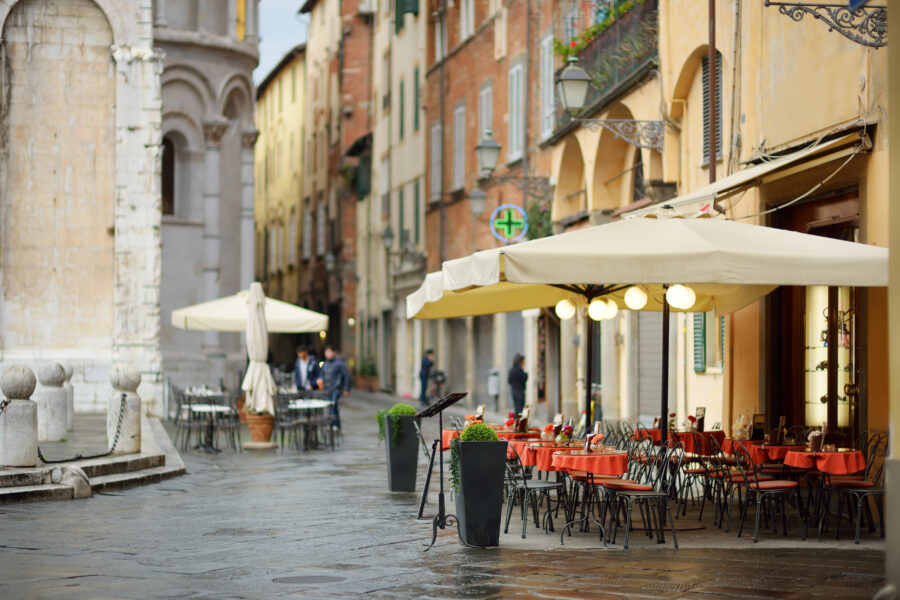 Small outdoor restaurant tables in Lucca, Italy, adorned with beautiful decorations, set against a charming city backdrop