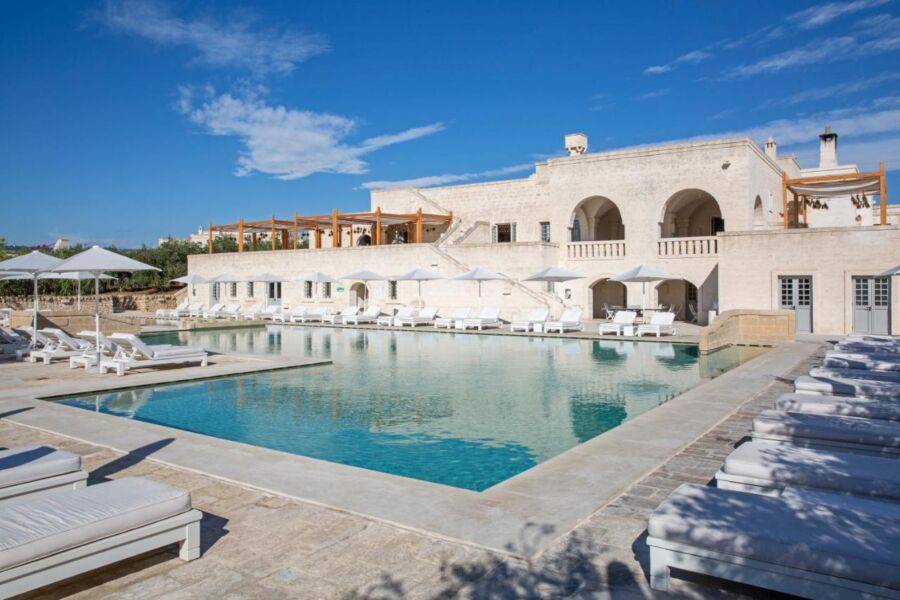 Luxurious resort with pool, lounge chairs, and elegant architecture in a serene setting.
