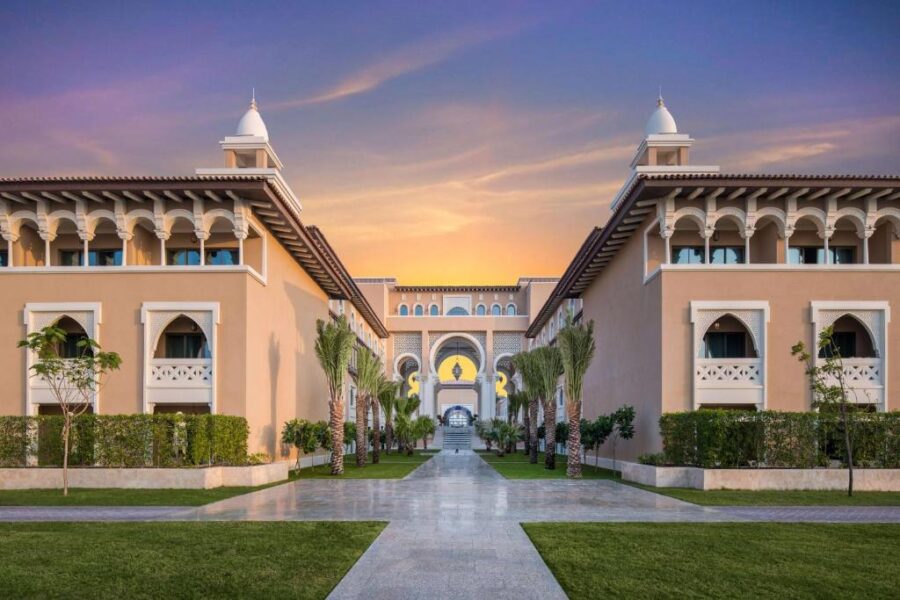 Luxury Saadiyat Island resort entrance at dusk with symmetrical architecture, palm trees, and elegant walkway.