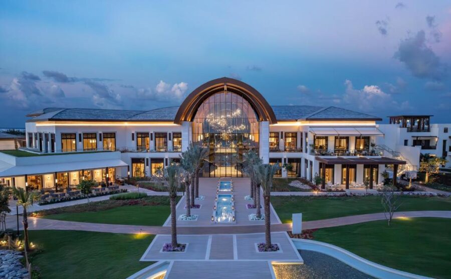 Luxury Anantara Mina Ras Al Khaimah resort entrance at dusk with palm trees and fountains.