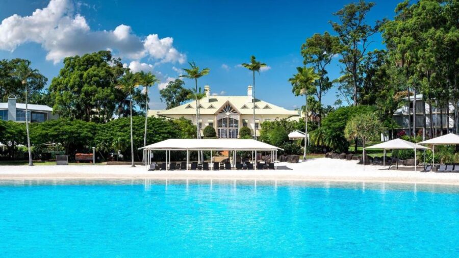 Luxury tropical resort lagoon pool with white sand beach, cabanas, palm trees, and hotel.