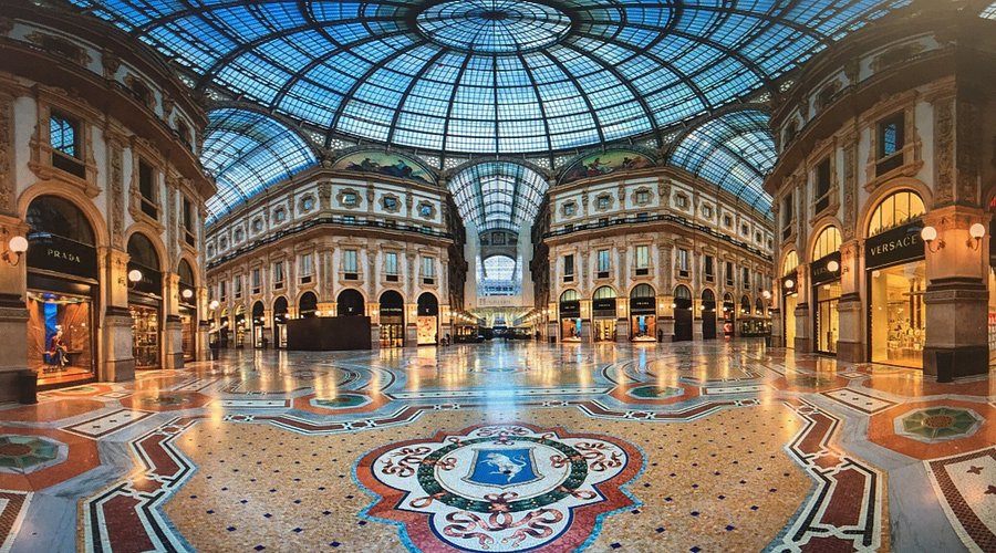 Elegant Milan shopping arcade with iron dome, mosaics, designer boutiques, and historical architecture.