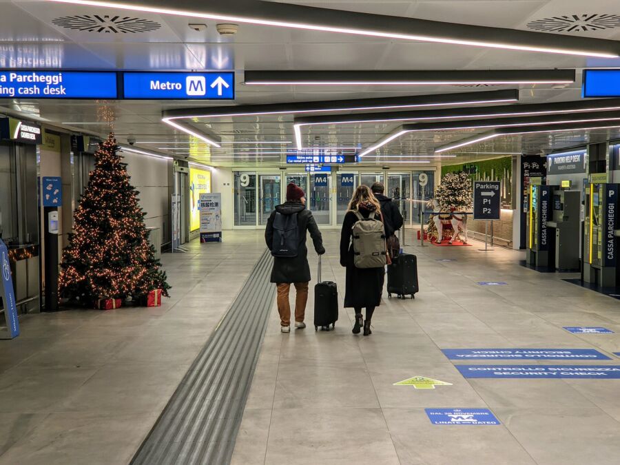 Passengers navigating the M4 Linate Airport train station's arrival area.
