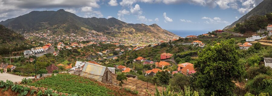Scenic view of Machico village nestled in the mountains of Madeira, showcasing lush greenery and traditional architecture.
