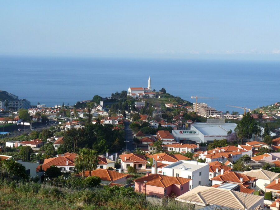 Hilltop perspective of a town and the sea in Madeira Islands, Portugal, featuring vibrant colors and stunning coastal scenery.


