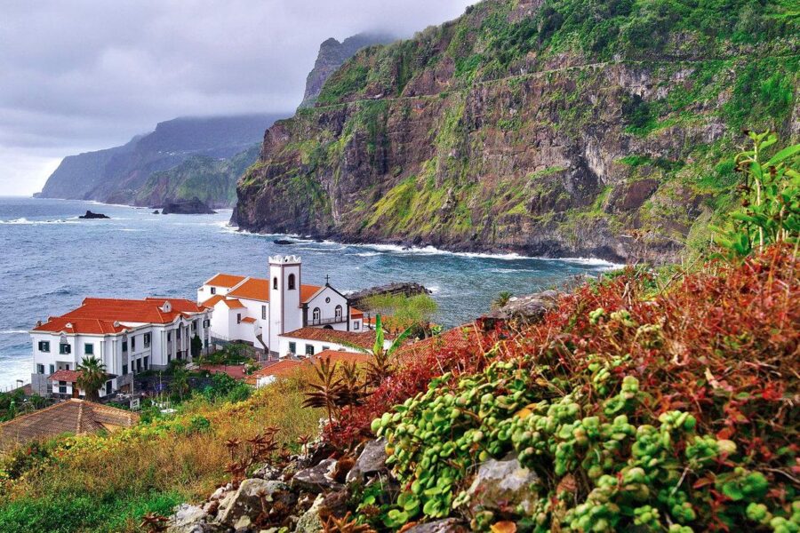 Scenic view of a small village perched on a cliff by the ocean, located in the Madeira Islands, Portugal.
