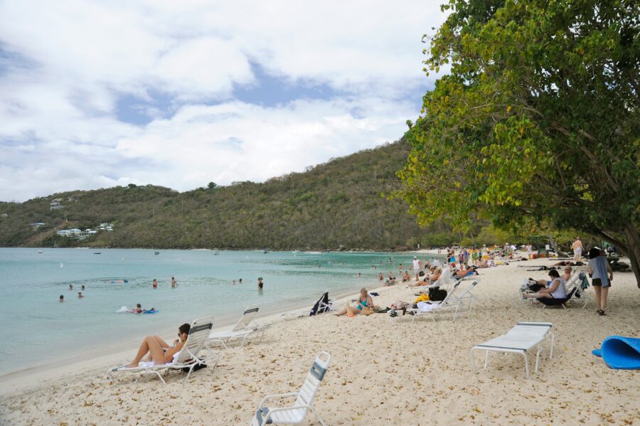 Magens Bay in St. Thomas, featuring a sandy beach where visitors relax under the sun and enjoy the tranquil atmosphere.