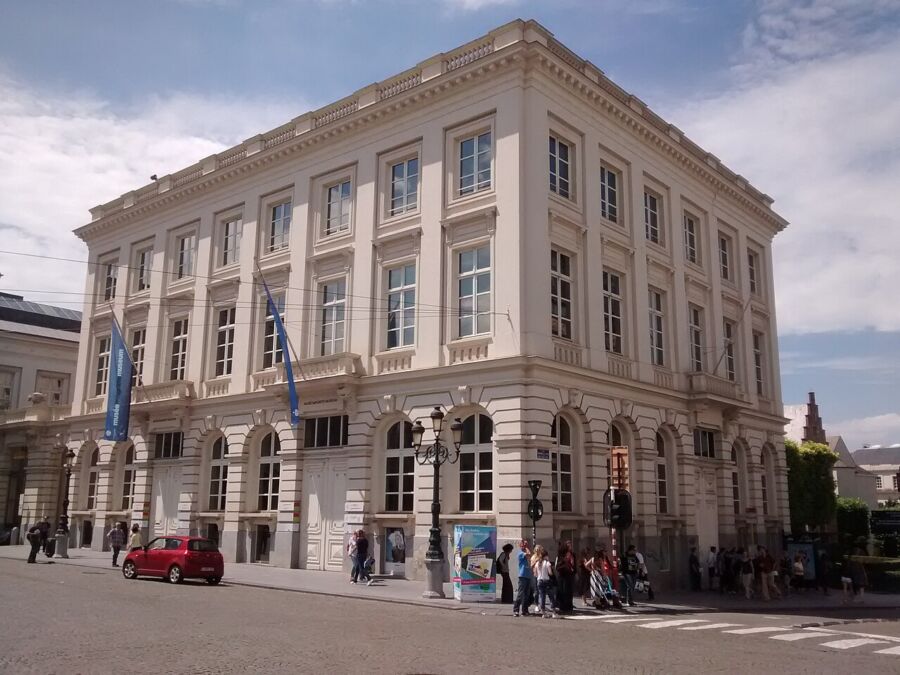 The Magritte Museum, Brussels, showcasing its grand architecture and surrounding gardens, under a clear blue sky.