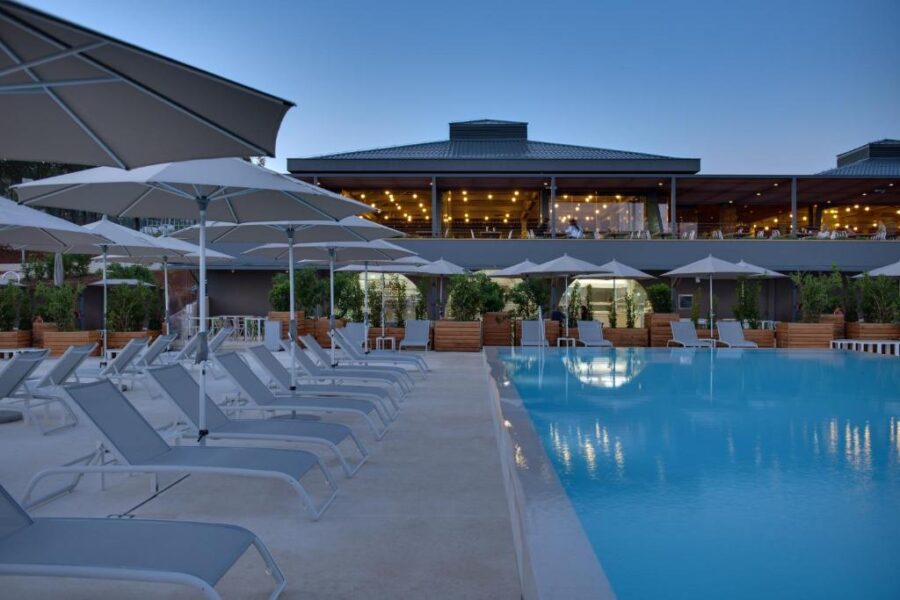 Pool at dusk, surrounded by lounge chairs and umbrellas, at the Maistra Select Amarin Resort.