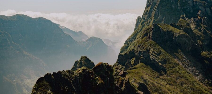 Breathtaking Madeira mountains: jagged peaks, lush greenery, swirling clouds, and rugged cliffs.