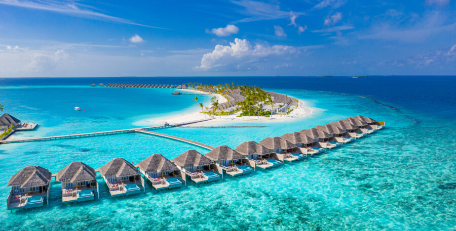 Stunning view of a Maldives resort featuring elegant bungalows set against a backdrop of clear blue skies and ocean