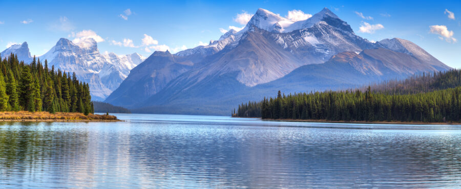 Scenic panorama of Maligne Lake, featuring vibrant blue waters and towering peaks in Jasper National Park.
