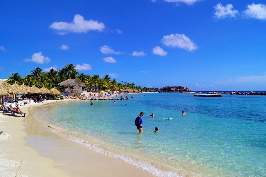 People relax and enjoy the sun at Mambo Beach, a vibrant tropical resort in Curacao.
