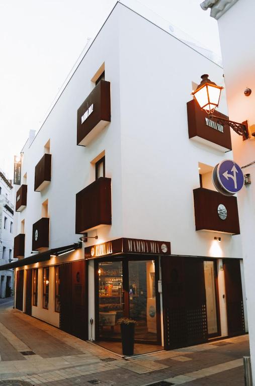 White building with brown windows and balconies, Mamma Mia Hotel Boutique for adults in Tossa de Mar, Spain.