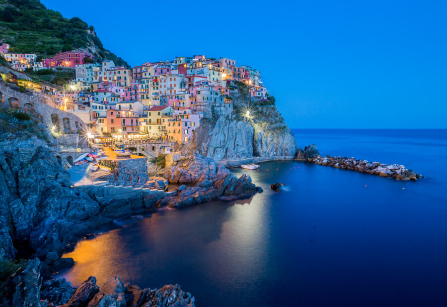 Evening view of Manarola, Cinque Terre, featuring twinkling lights that enhance the picturesque seaside scenery