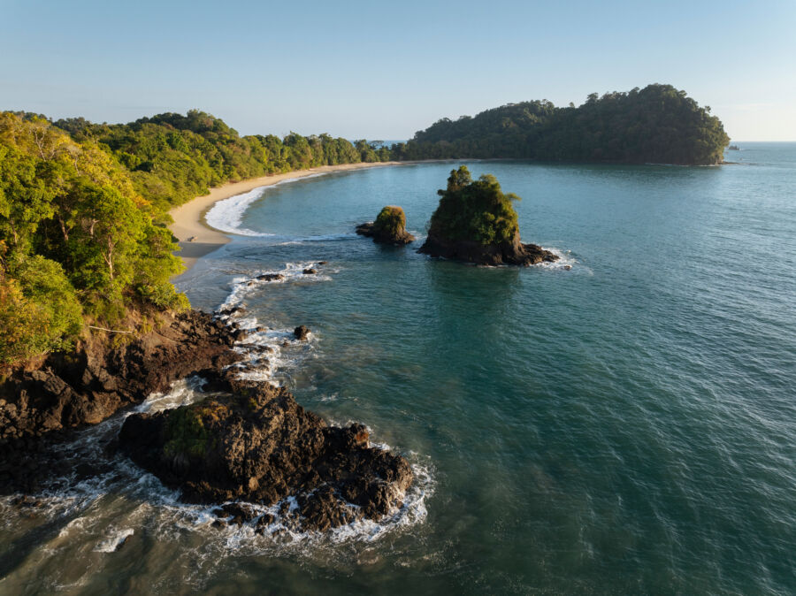 Scenic view of Manuel Antonio Beach within Manuel Antonio National Park, showcasing golden sands and lush greenery