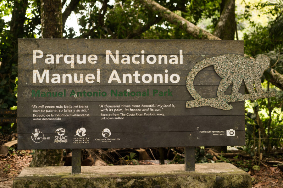Entrance sign for Manuel Antonio National Park in Puntarenas, Costa Rica, featuring lush greenery in the background