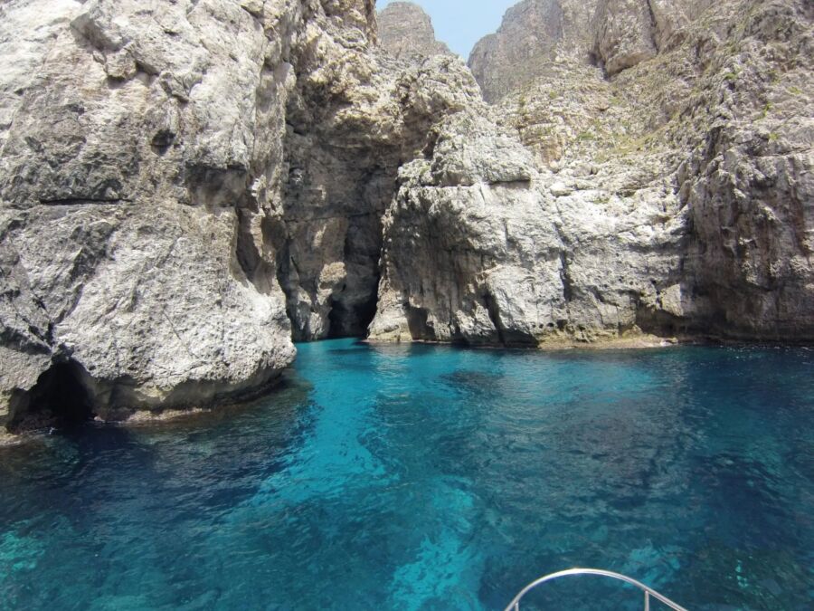 Marettimo Sea Cave rocky cliffs surround a vibrant, turquoise sea, with a small cave nestled between the rocks. The scene feels tranquil and secluded.
