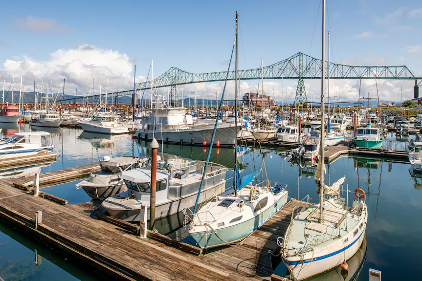 Astoria, Oregon marina with docked sailboats, wooden docks, steel bridge and reflections.