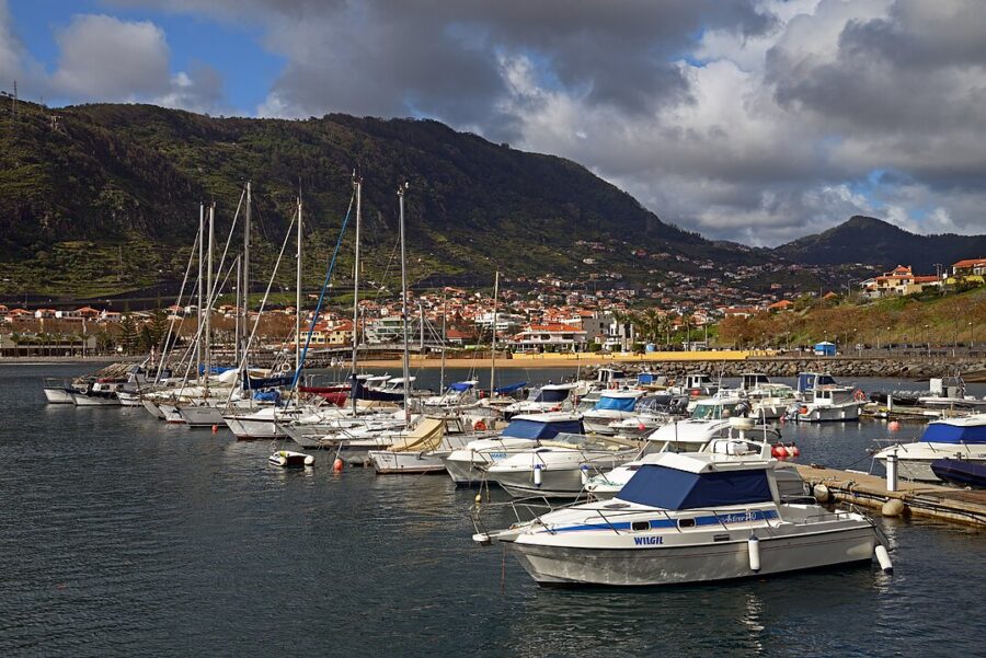 Several boats floating in the water at the Marina of Machico, Madeira, Portugal, surrounded by scenic coastal views.
