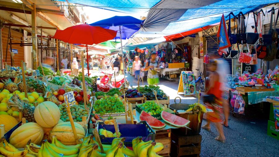 Busy open-air market with colorful fruits, vegetables, and vibrant community interactions.