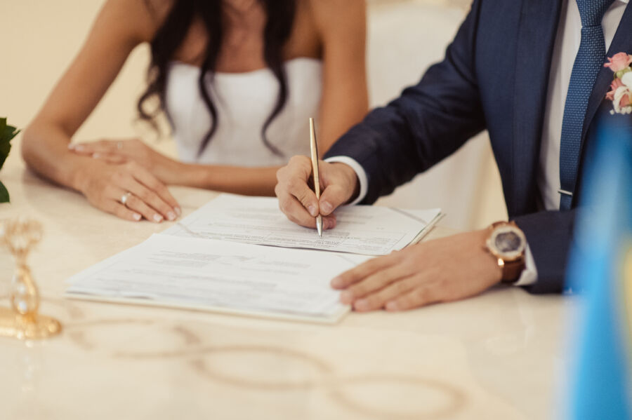 The bride and groom sign their marriage documents during a signature ceremony