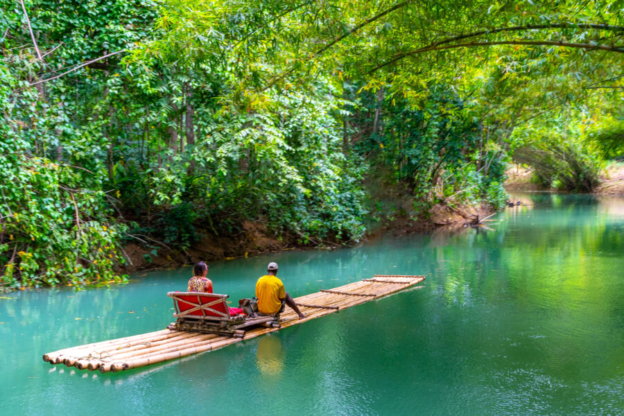 Female tourist and her guide relax on a bamboo raft floating on the Martha Brae River in Falmouth, Jamaica