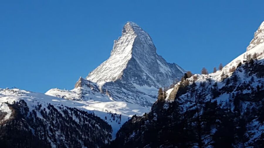 The iconic Matterhorn mountain towering over Zermatt, Switzerland, with its distinctive pyramid shape against a clear blue sky.
