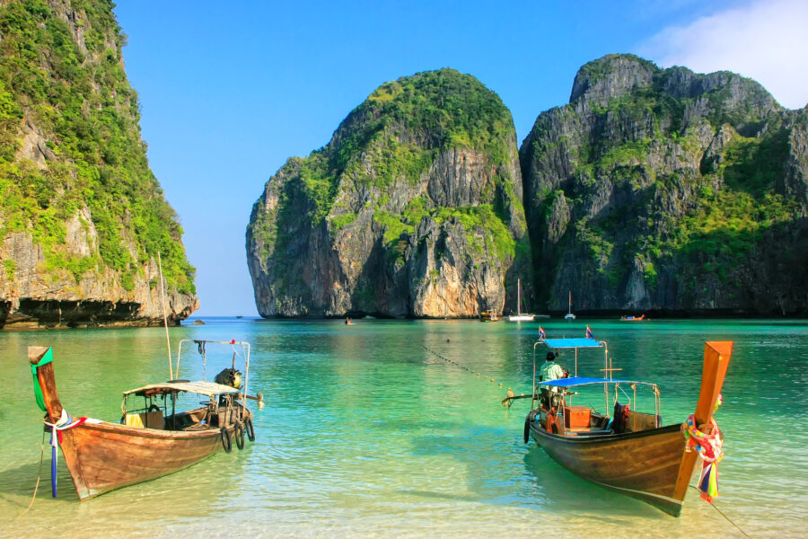 Scenic view of longtail boats moored at Maya Bay, Phi Phi Leh Island, with dramatic cliffs and clear blue waters