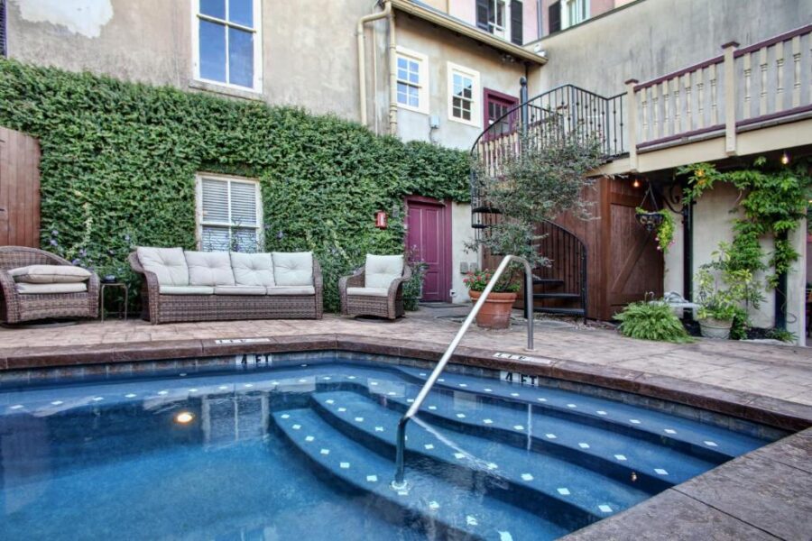 The courtyard of McMillan Inn in Savannah, Georgia, showcasing a tranquil pool, patio area, and elegant stairs.
