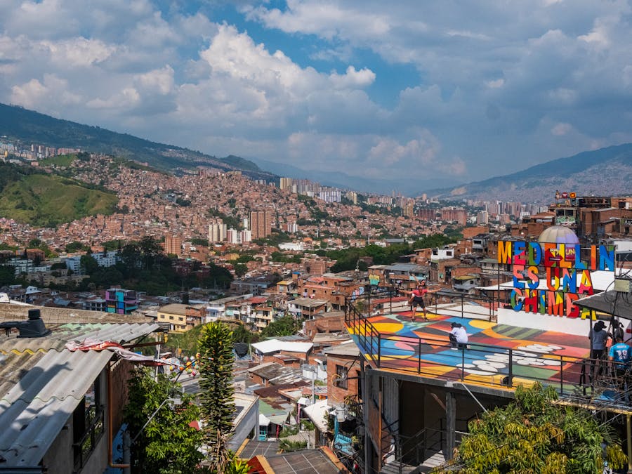Vibrant urban Medellín: colorful murals, bustling terrace, dramatic hills.