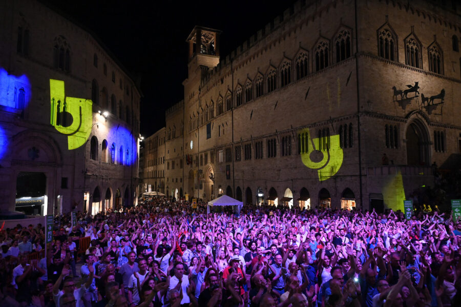 Perugia Umbria Jazz Festival crowd in medieval square at night under colorful stage lighting.
