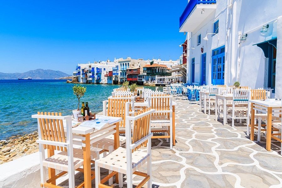 Mediterranean seaside dining with vibrant architecture, serene waters, and rustic charm.
