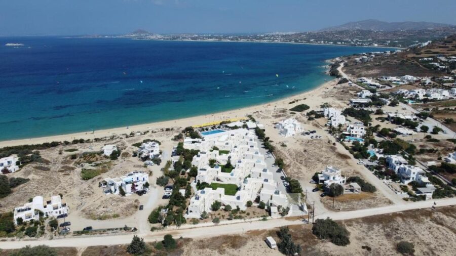 Aerial view of Mediterranean coastal village with sandy beach, azure sea, and white buildings.